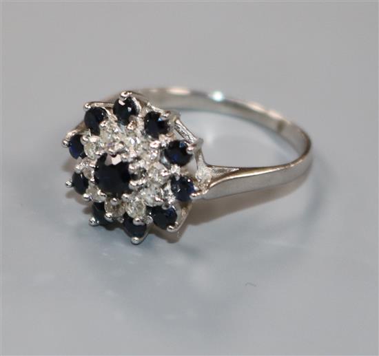 A modern 18ct white gold, sapphire and diamond cluster dress ring, size S.